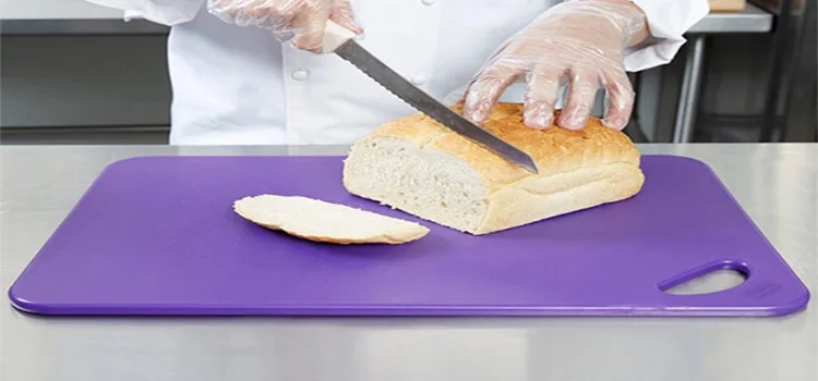 A chef is cutting bread on a purple chopping board