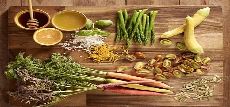 various types of vegetables and honey on a wooden chopping board 