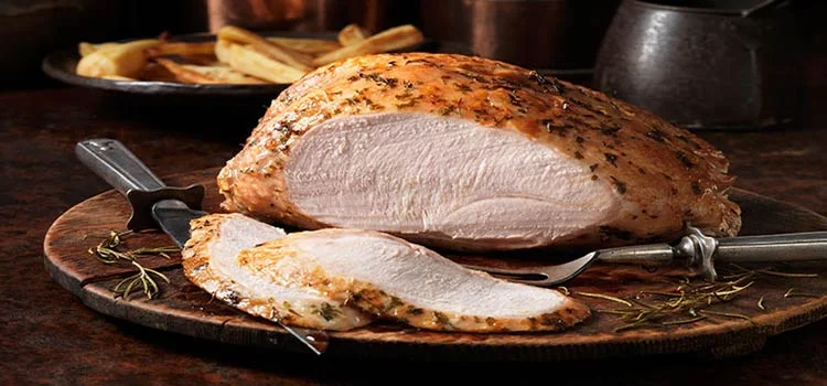 Grilled turkey sliced on a plate with knives