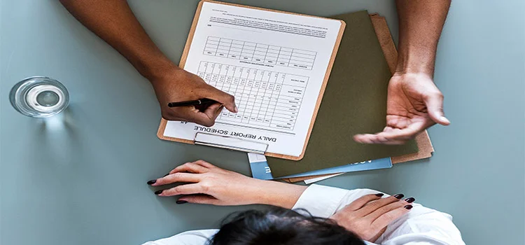 A person is showing the daily report schedule to a woman