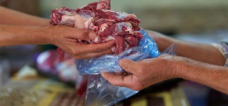 A man is buying a packet full of raw meat