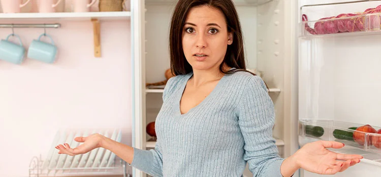  Confused young woman in front of open refrigerator
