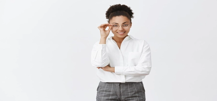  A good-looking, stylish and smart female psychologist with dark skin tone in a white-collar shirt and pants smiling against a white background. 