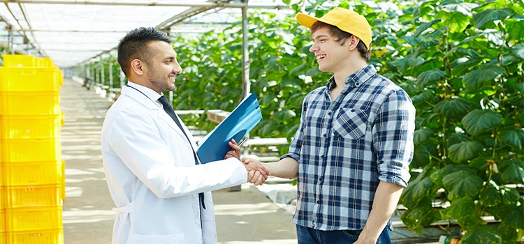 Close-up of researcher and farmer shaking hands during their happy conversation 