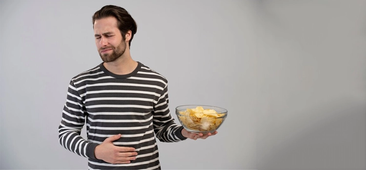 Man with an eating disorder experiencing stomach discomfort while holding a bowl of fried chips 