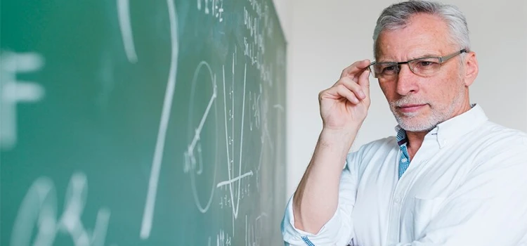 Close-up of concentrated university math professor looking at chalkboard